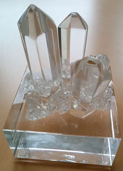 Photo d'un Cristal collectif du CNRS : 3 cristaux de roche posés sur un socle transparent.